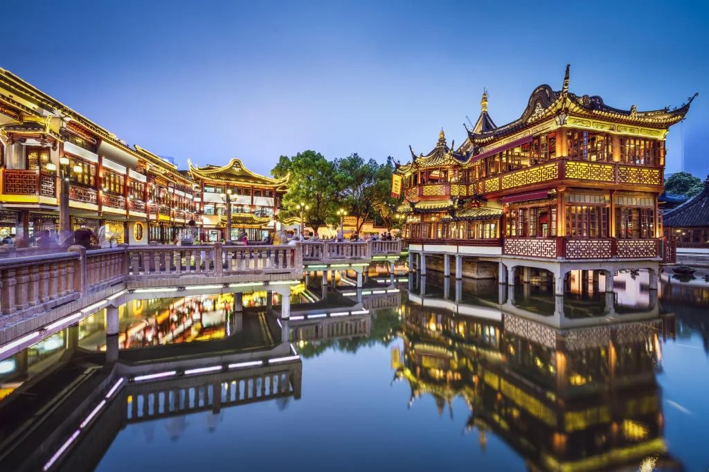 Traditional Chinese pavilion and Nine-Bend Bridge at Yu Garden with red lanterns reflecting in the water